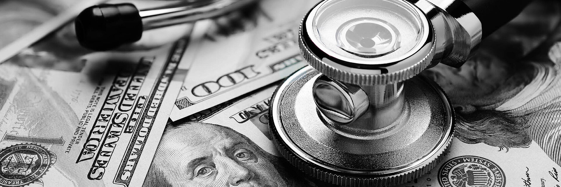 Black and white image of US 100-dollar bills and a stethoscope