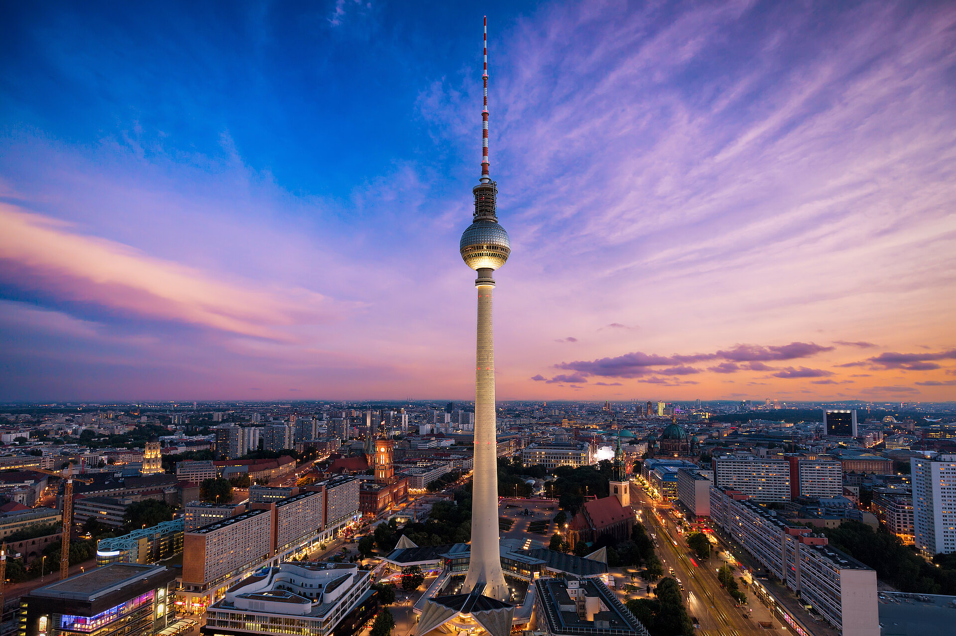 Berliner Fernsehturm über der Stadtkulisse bei Sonnenuntergang.