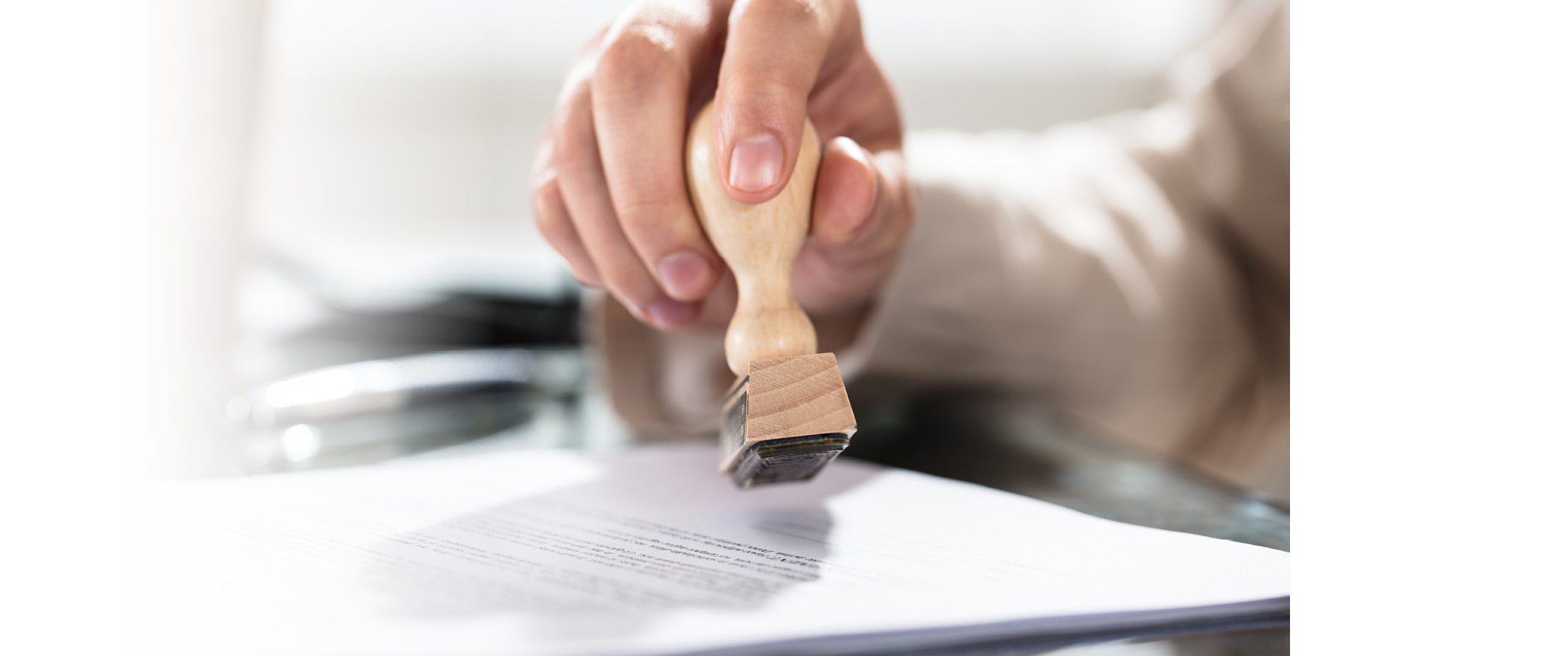 Close-up Of A Person's Hand Stamping On Approved Application Form Over The Desk